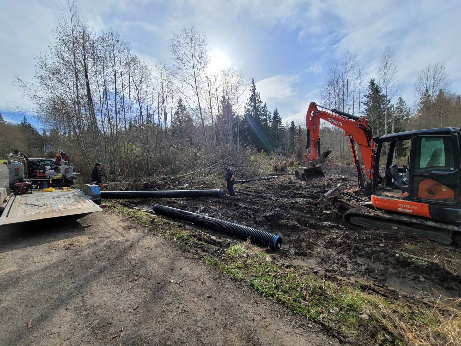 Workers from Salish Excavation and Trucking LLC laying sewer pipes in trench